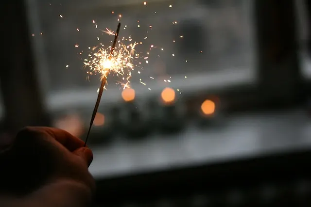 person holding lighted sparklers in the new year eve